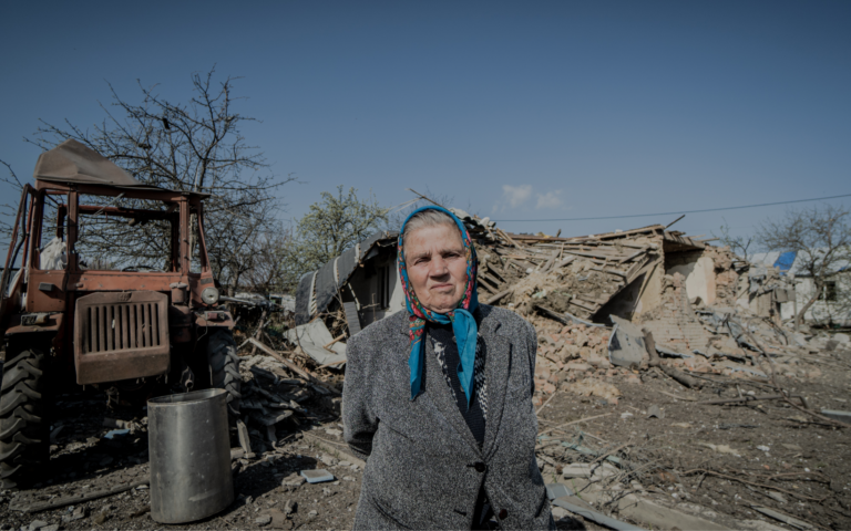 A resident of Velyki Prokhody, Kharkiv region. Russians dropped an aerial bomb on the village on April 11, 2024. Her house, destroyed by the bomb, is behind her. / Photo: Ivan Samoilov for Gwara Media