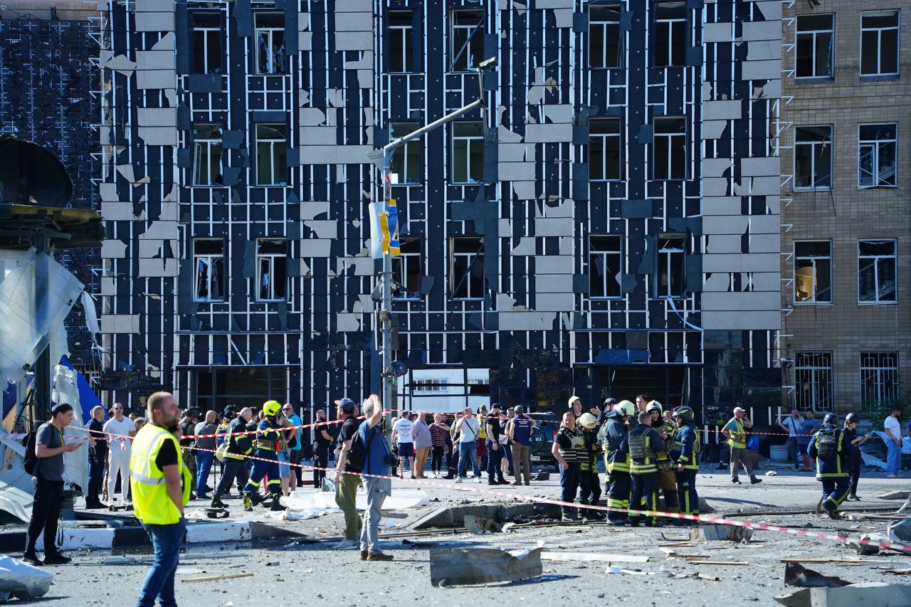 People standing in front of a building damaged by a Russian glide bomb attack on the center of Kharkiv on June 22, 2024