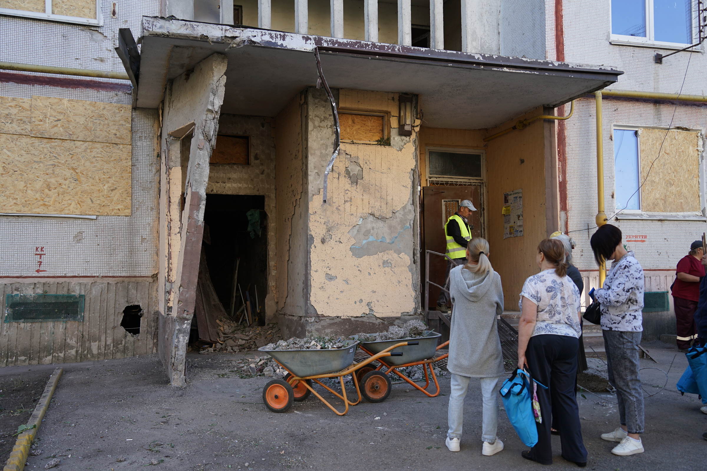 People standing near high-rise heavily damaged by Russians bombardment of Kharkiv on September 24 / Photo: Daria Lobanok, Gwara Media