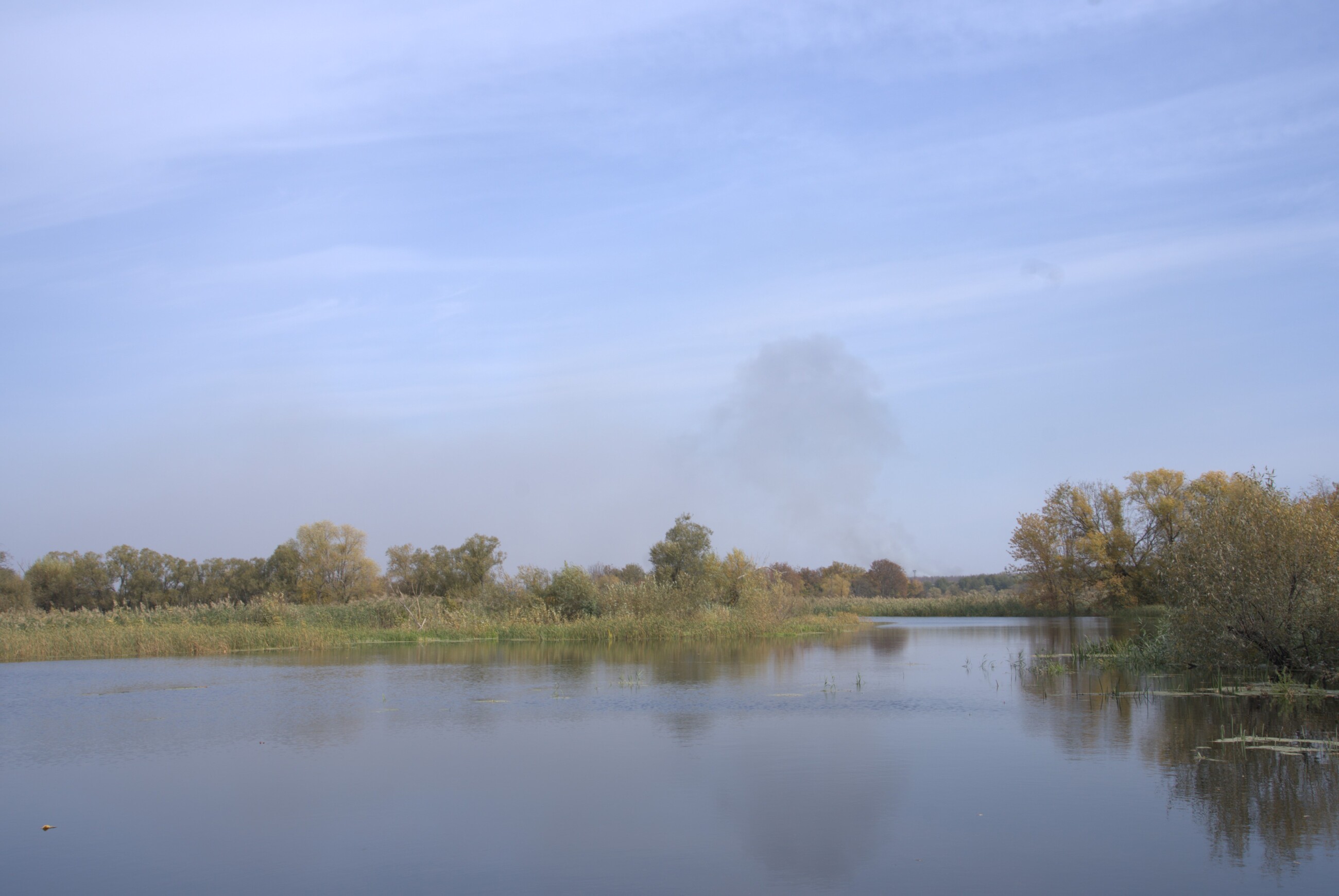 View from the Oskil River. The smoke from the impact of Russian glide on the left bank is seen on the background. October 2024 / Photo: Yana Sliemzina, Gwara Media