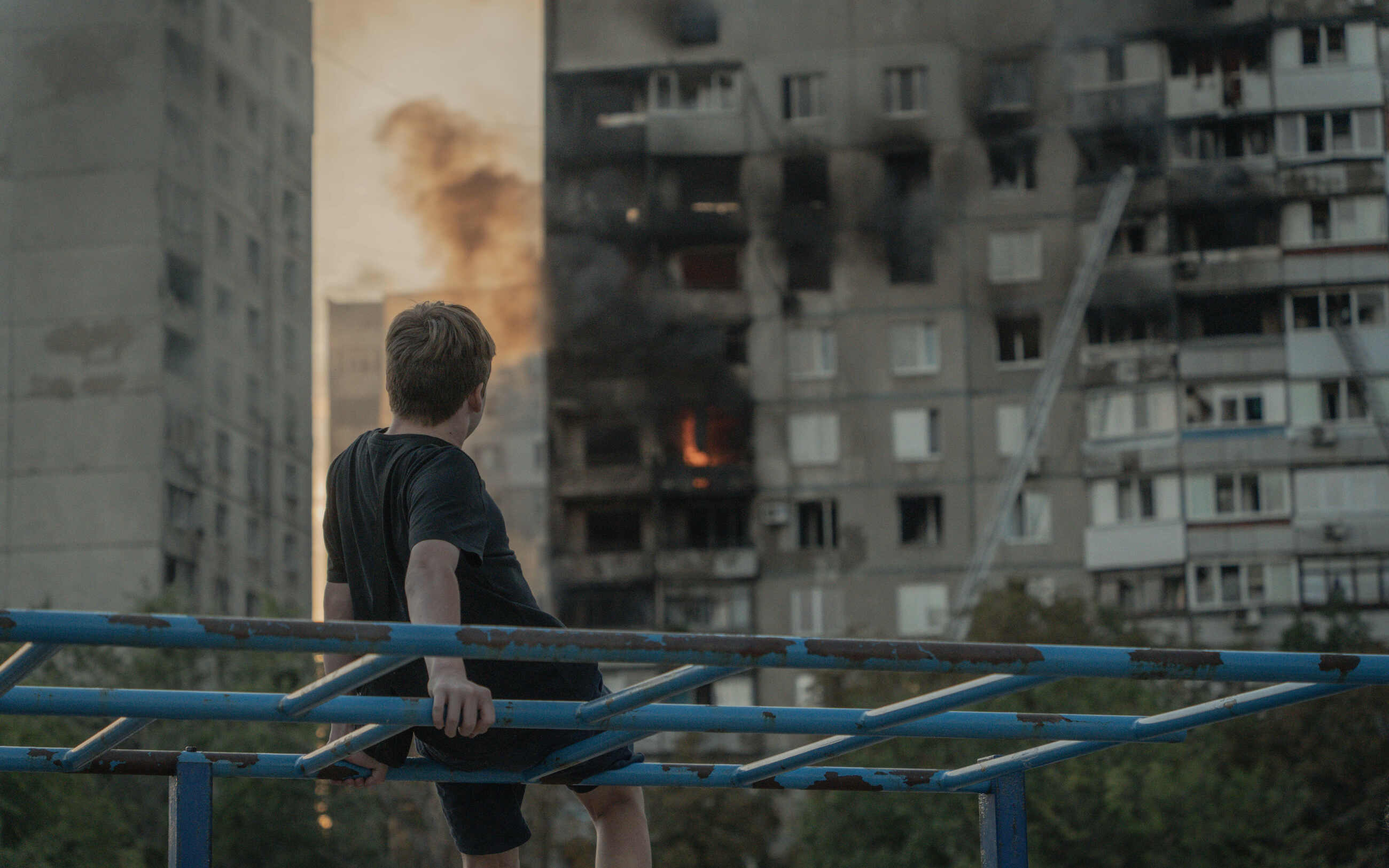 A boy watching a residential high-rise in Kharkiv burning after a Russian glide bomb hit it on August 30, 2024 / Photo: Ivan Samoilov, Gwara Media