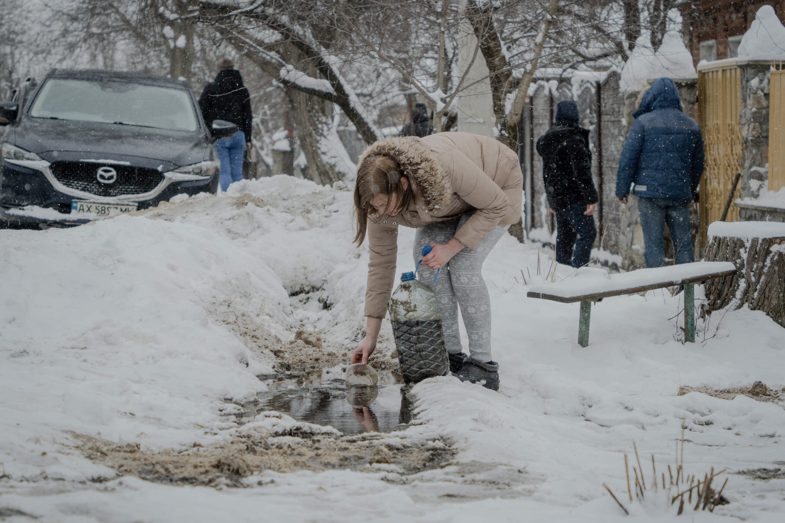 Local resident gathers oil from a puddle after Russian air attack on oil plant in Nemyshlianskyi district of Kharkiv. The attack killed 7 people and burned down 15 houses. February 12, 2024 / Photo: Ivan Samoilov, Gwara Media