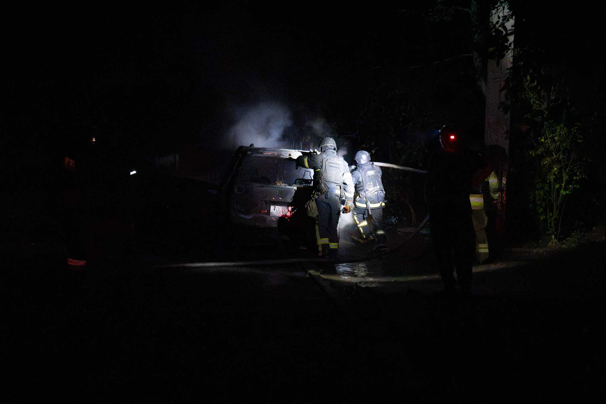 Rescuers extinguish a burning car