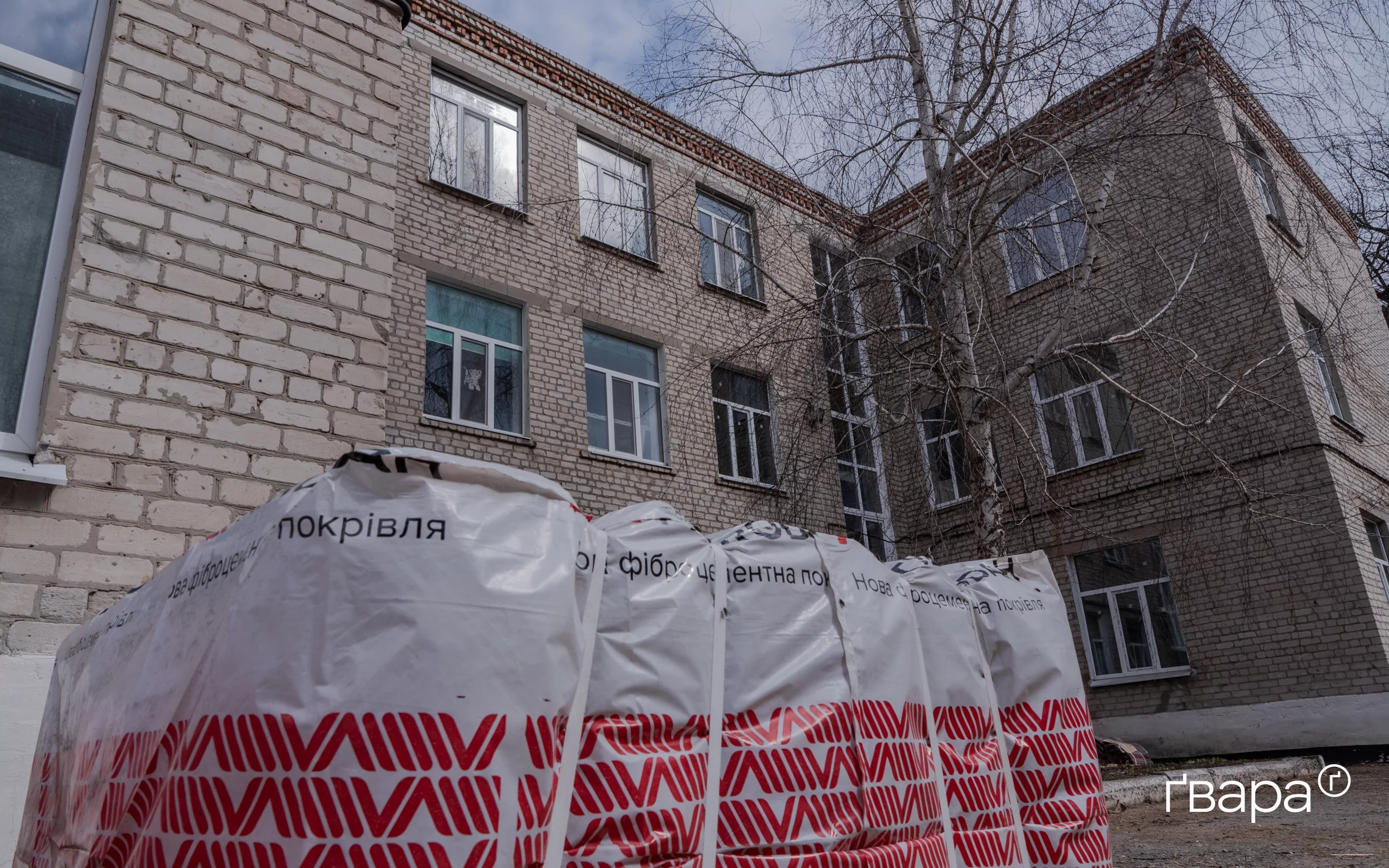 Будівельні матеріали, що призначені для відбудови даху на фоні відновлених вікон ліцею.