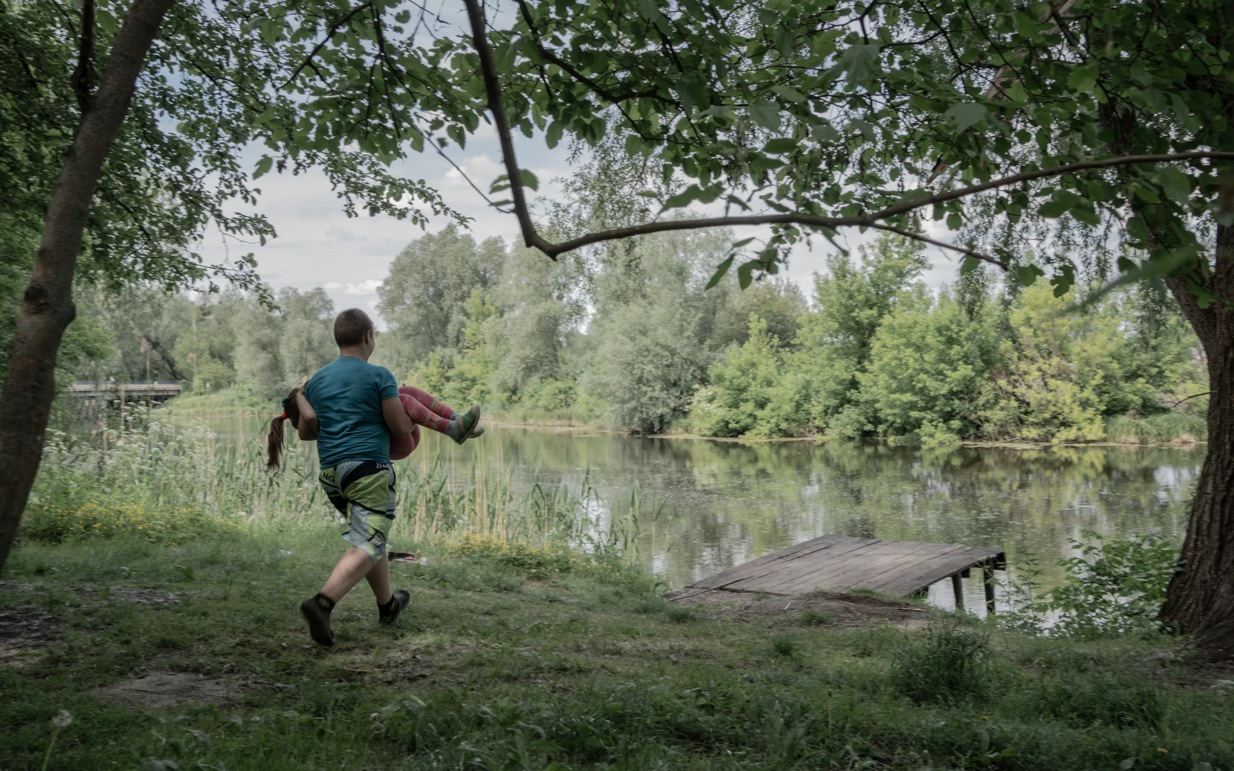 Yahor plays with Zlata walking towards the lake nearby their house in Zavodske, Poltava Oblast / Photo: Daria Lobanok, Gwara Media