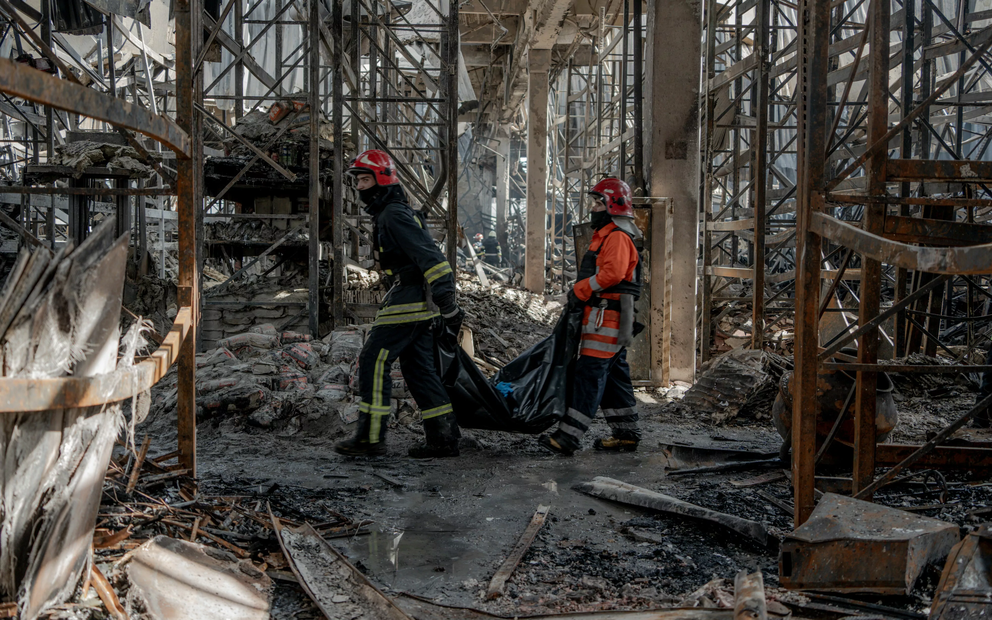 Працівники ДСНС виносять знайдене тіло загиблого у вщент Епіцентрі. Напередодні російська авіація обстріляла його 3 авіаційними бомбами. 26 травня 2024 / Фото: Іван Самойлов, Ґвара Медіа