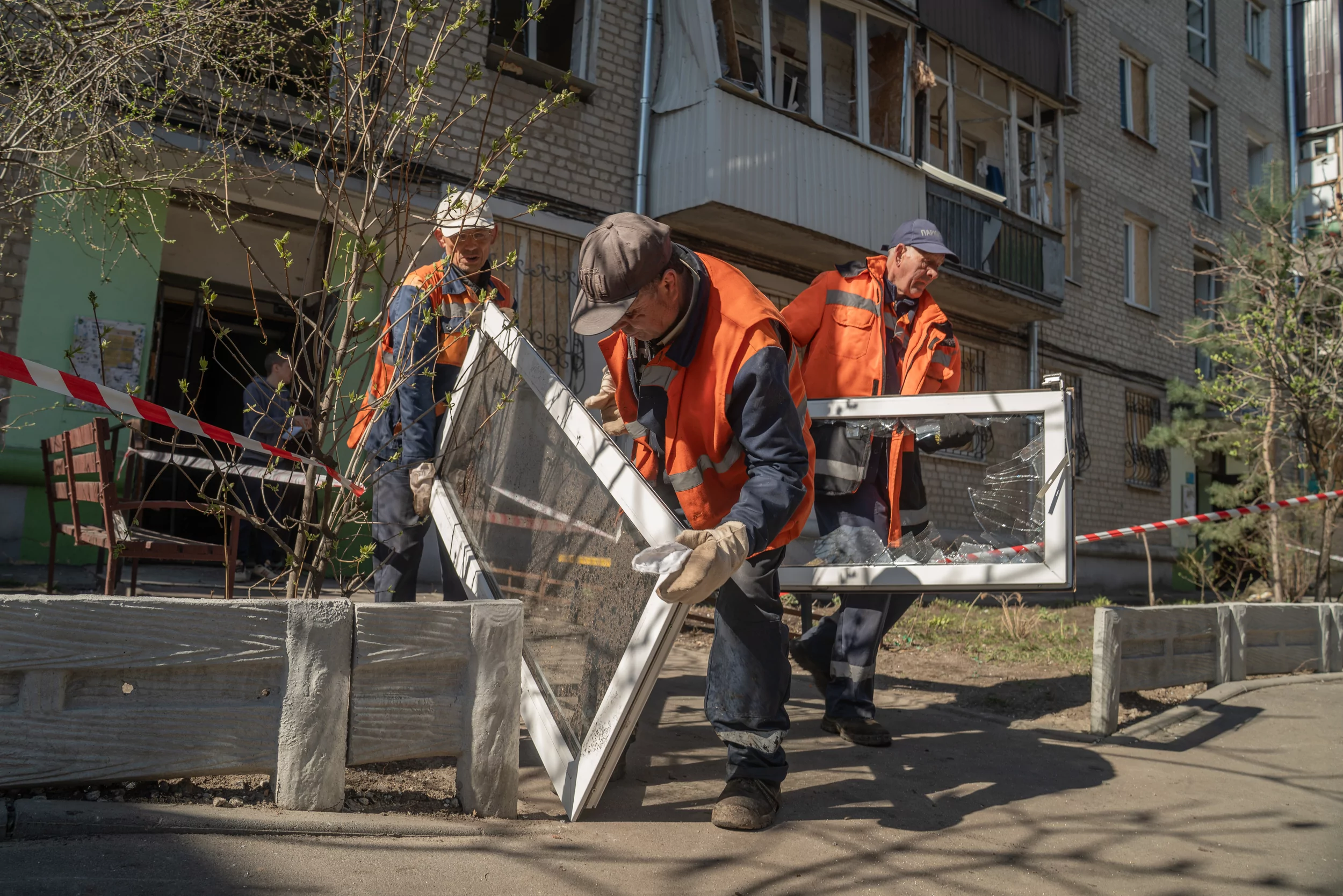 Municipal workers carrying the blown-out windows from building targeted by Russian drones in Kharkiv on April 3, 2025 / Photo: Hnat Holyk, Gwara Media