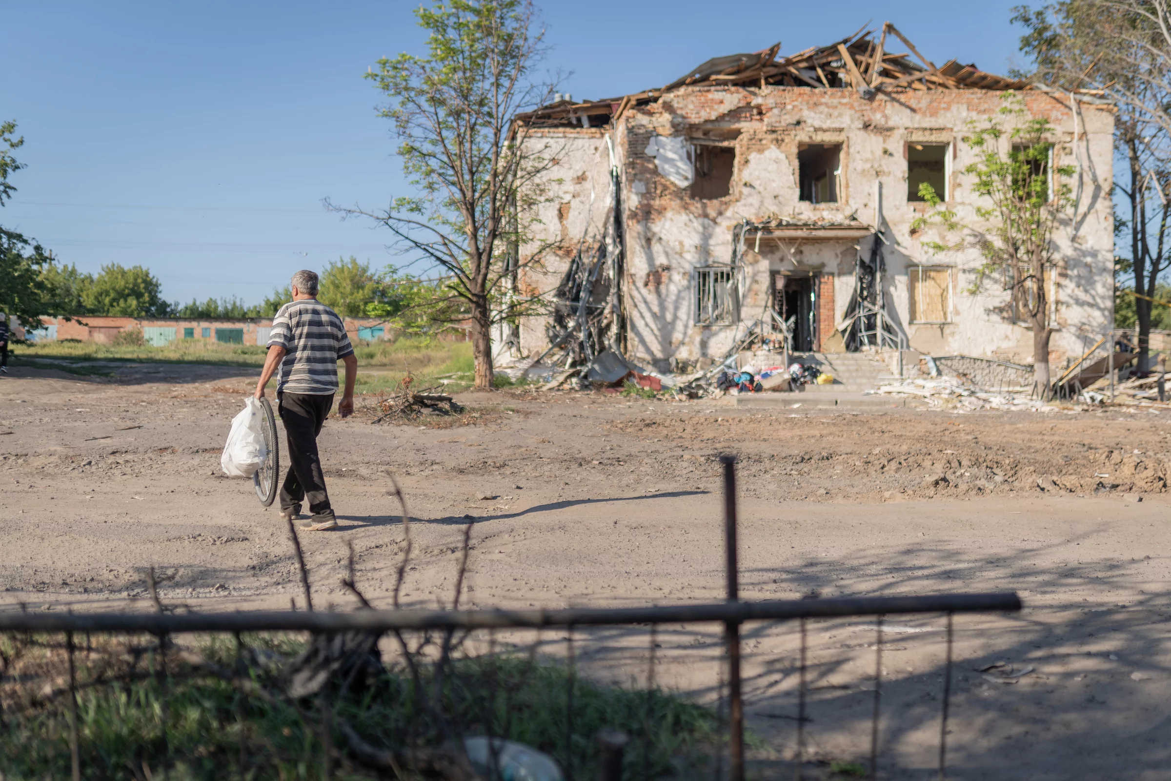A building that was damaged by Russian attacks, and a local man was walking nearby. Kupiansk district, Aug 2025
