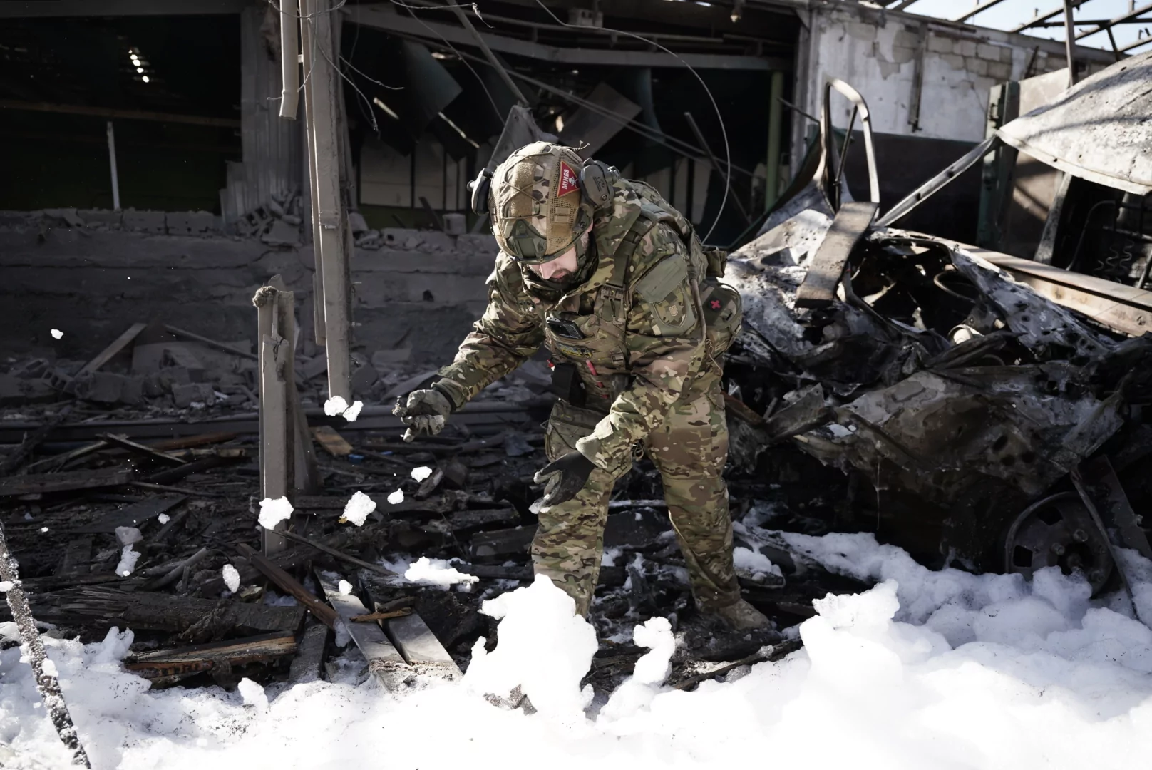 A man wearing military uniform, most likely a sapper, is at the impact site of Russian glide bomb attack on Kharkiv
