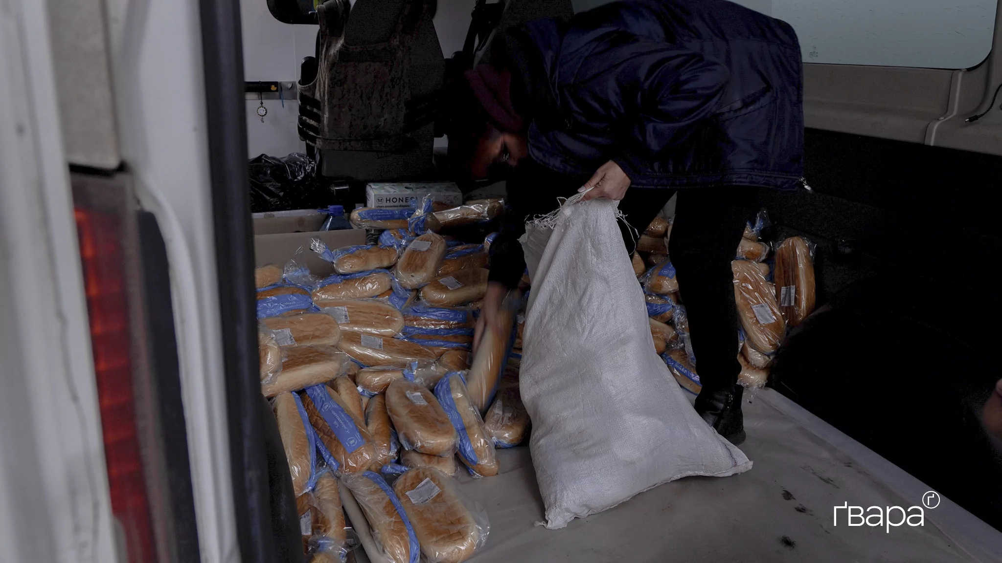 Людина у чорному одязі збирає білий хліб у мішок