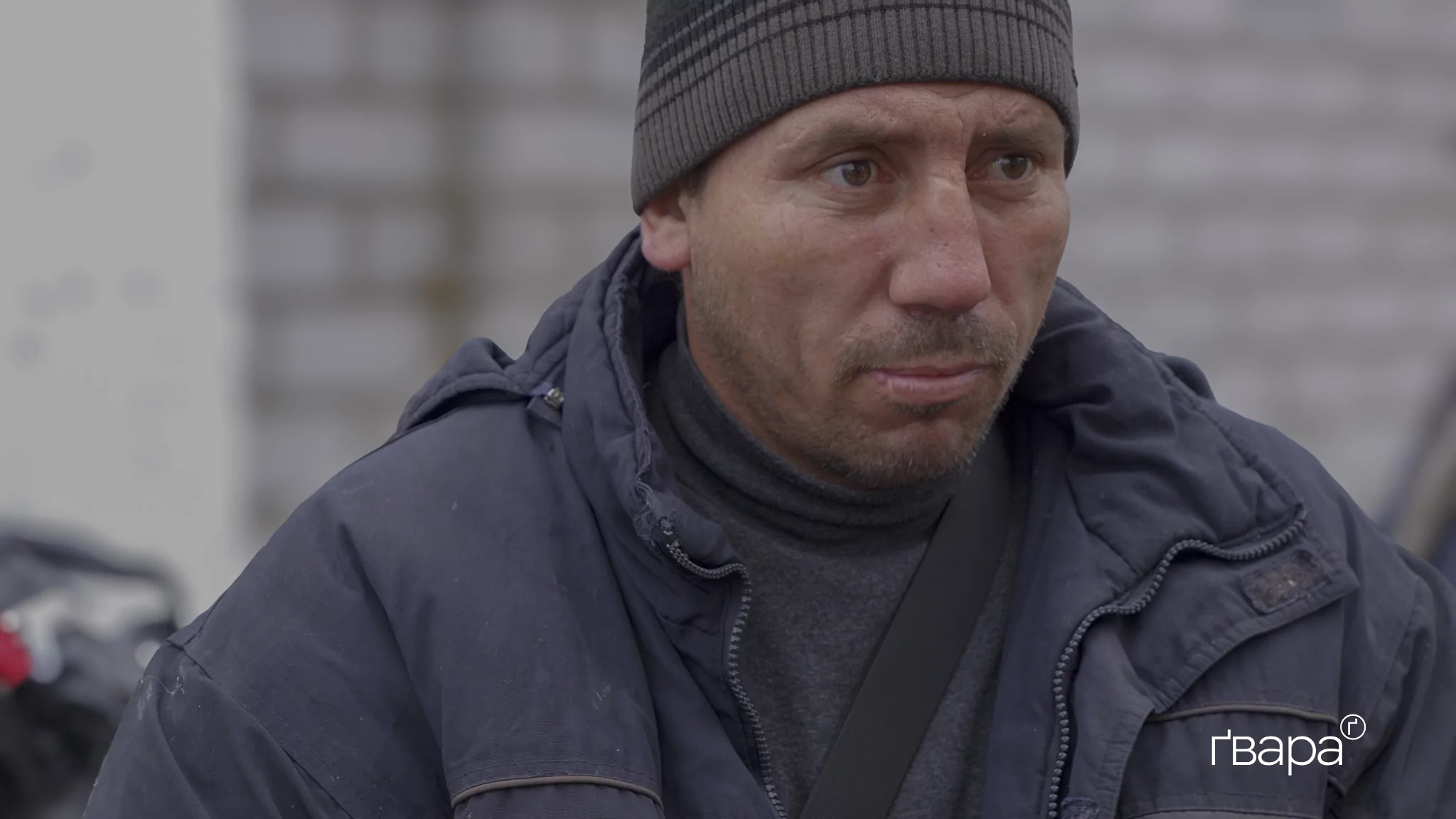 Чоловік у сірій шапці і синій куртці