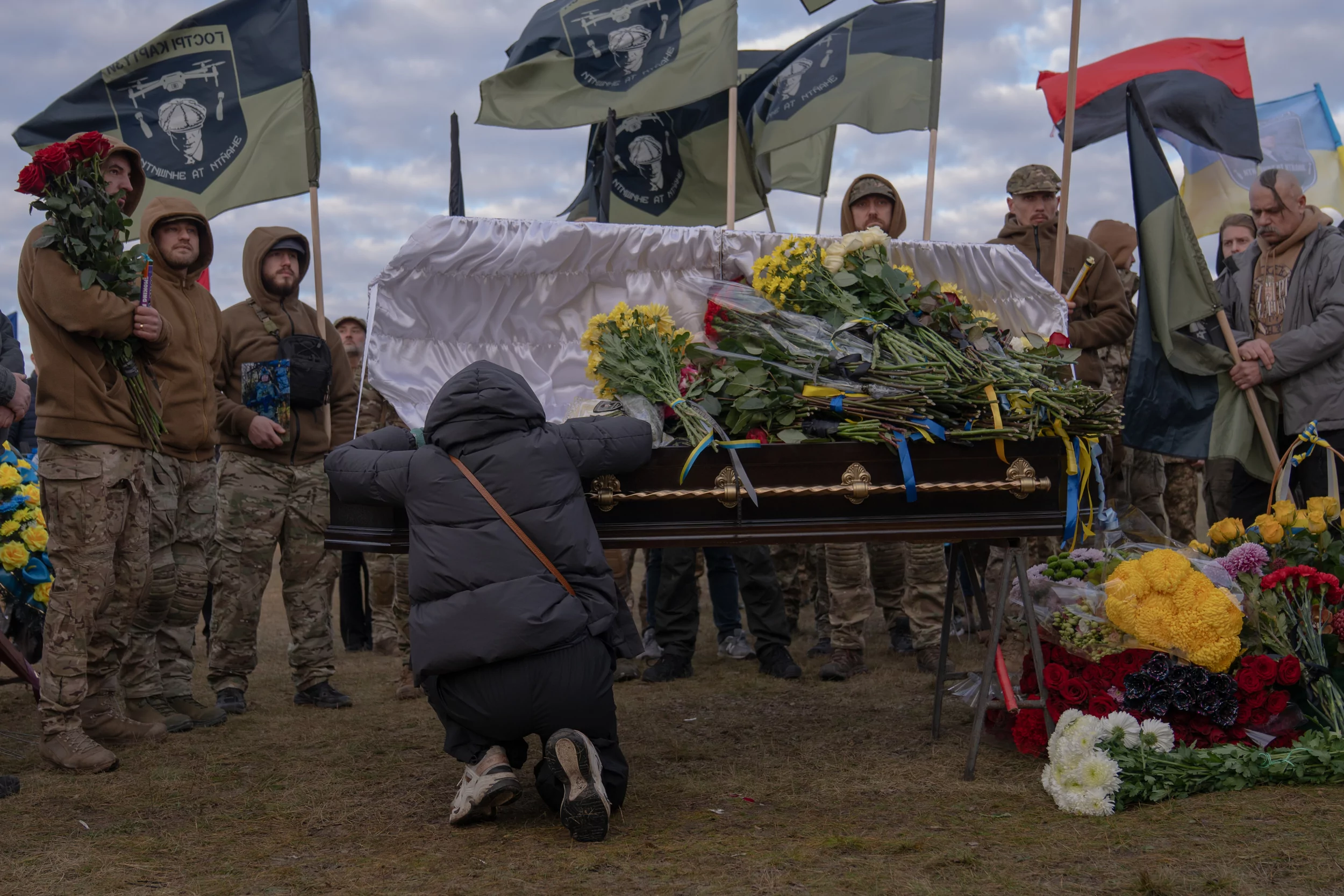 A woman sits next to the coffin of a killed volunteer from Kharkiv.
