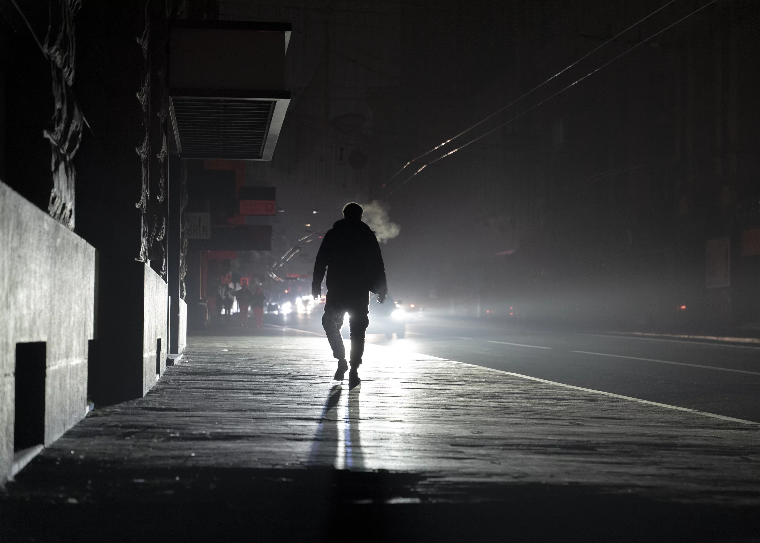 A man walks down a dark street during a blackout after another Russian attack on Kharkiv