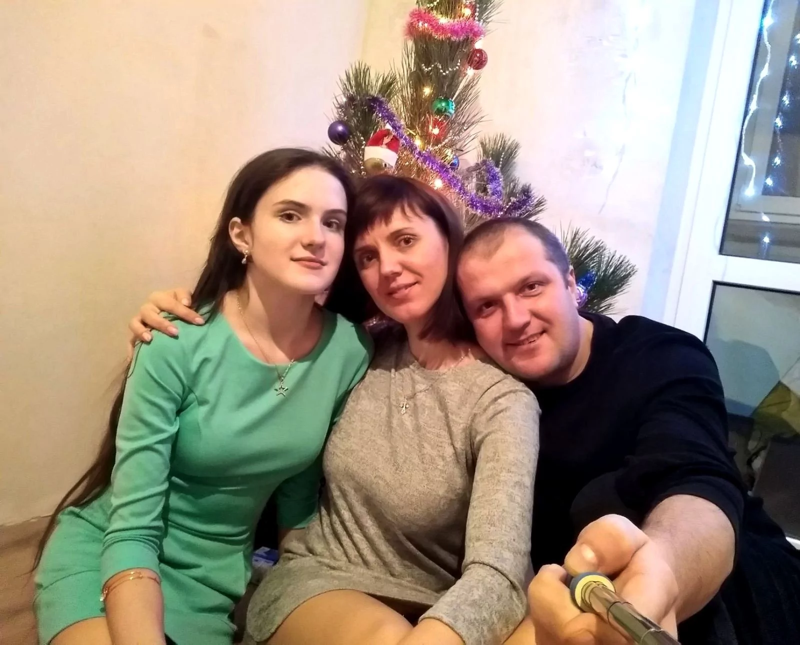 Дівчина у зеленому платті, жінка у сірій кофті і чоловік у чорній кофті, який тримає селфі-палку. Поліна, Людмила і Руслан.