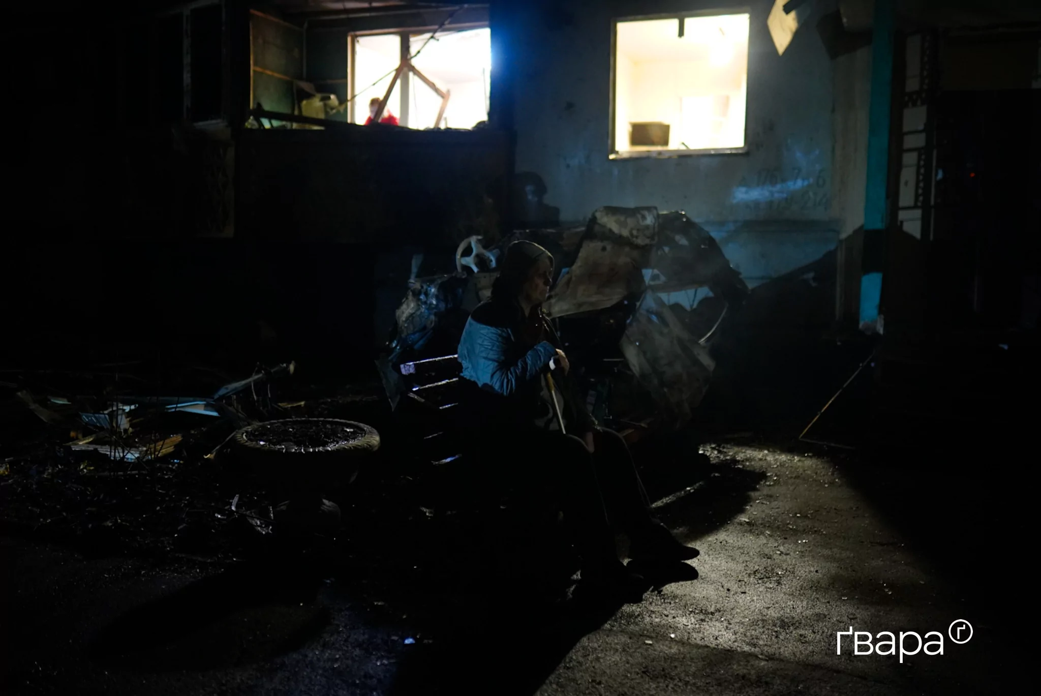 чоловік сидить біля зруйнованого будинку у Харкові