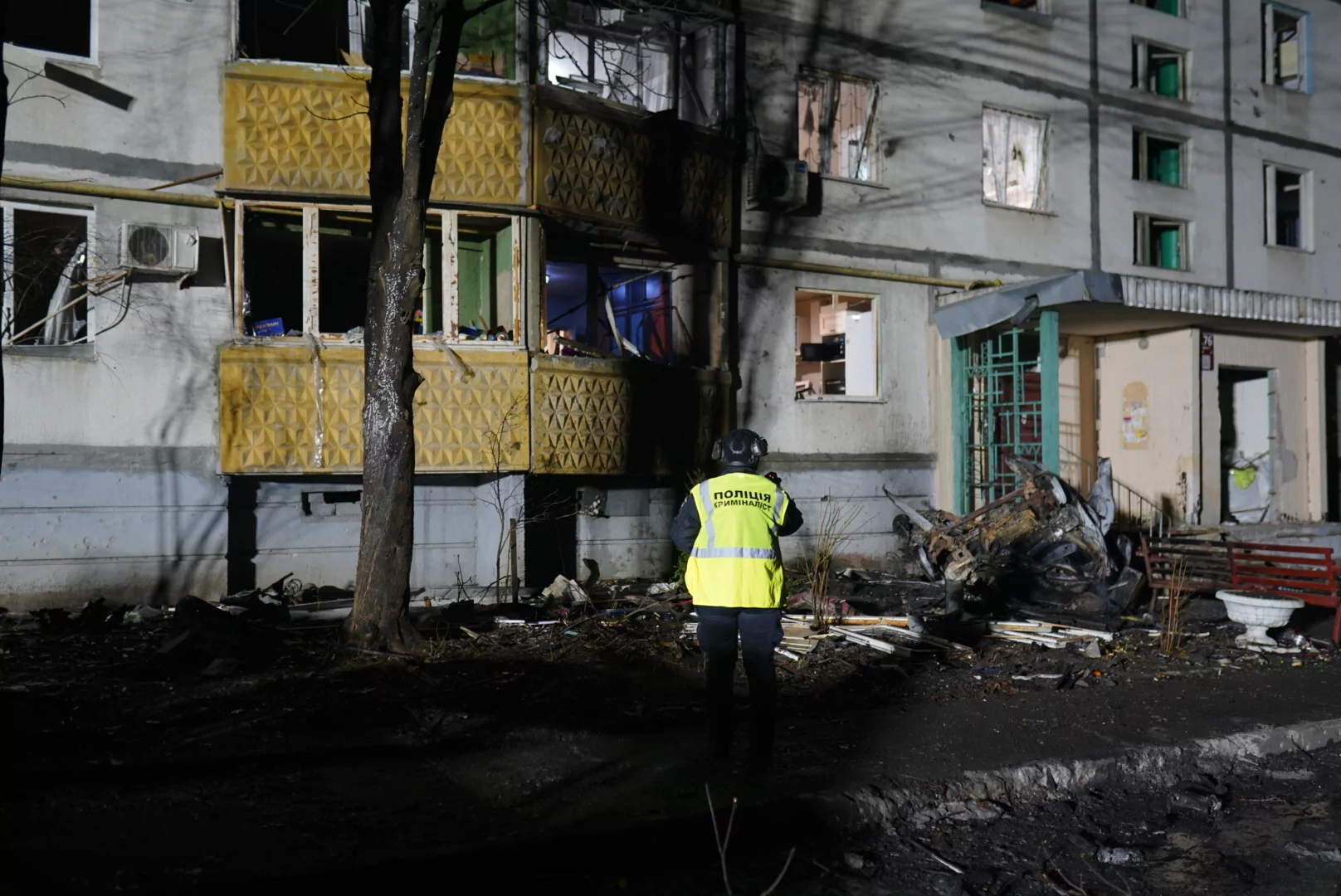 A police officer stands next to a damaged building after Russian attack on Kharkiv