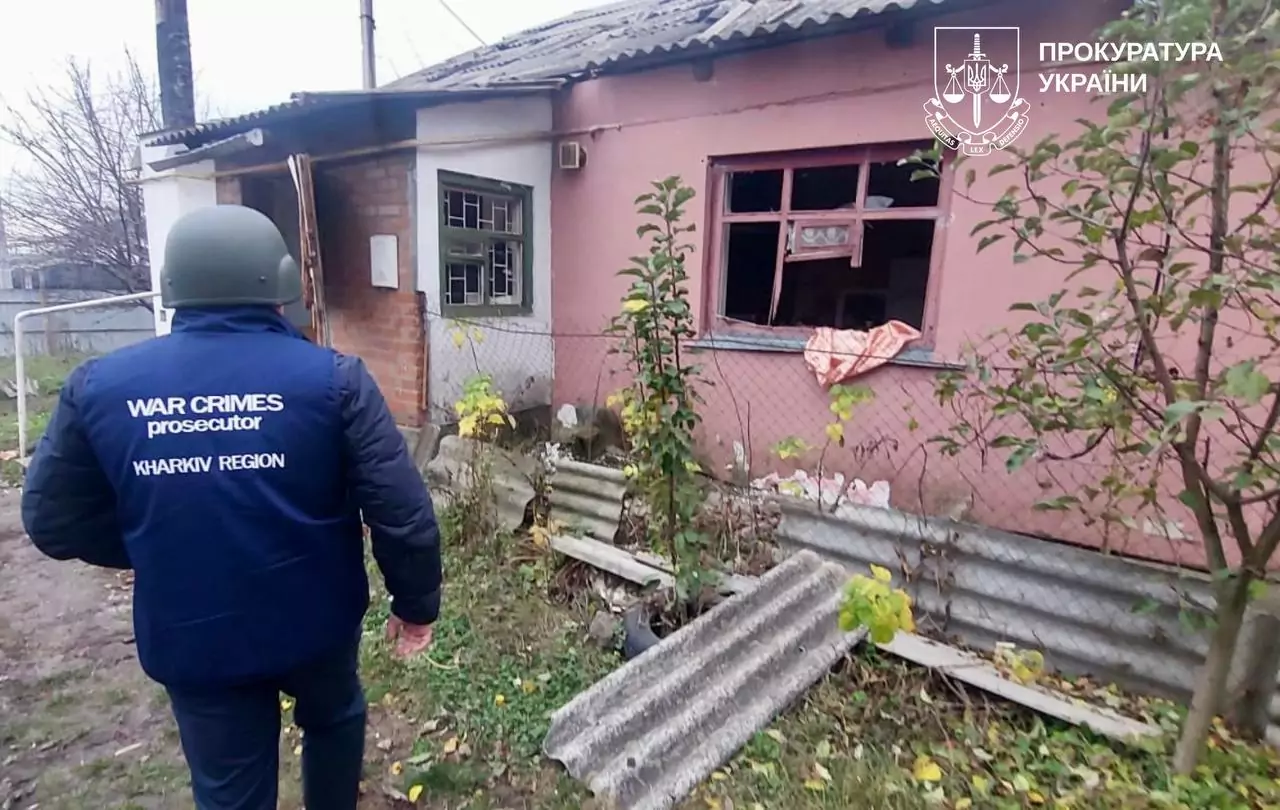A war crimes prosecutor stands next to a damaged house after the Russian attack on Berestyn