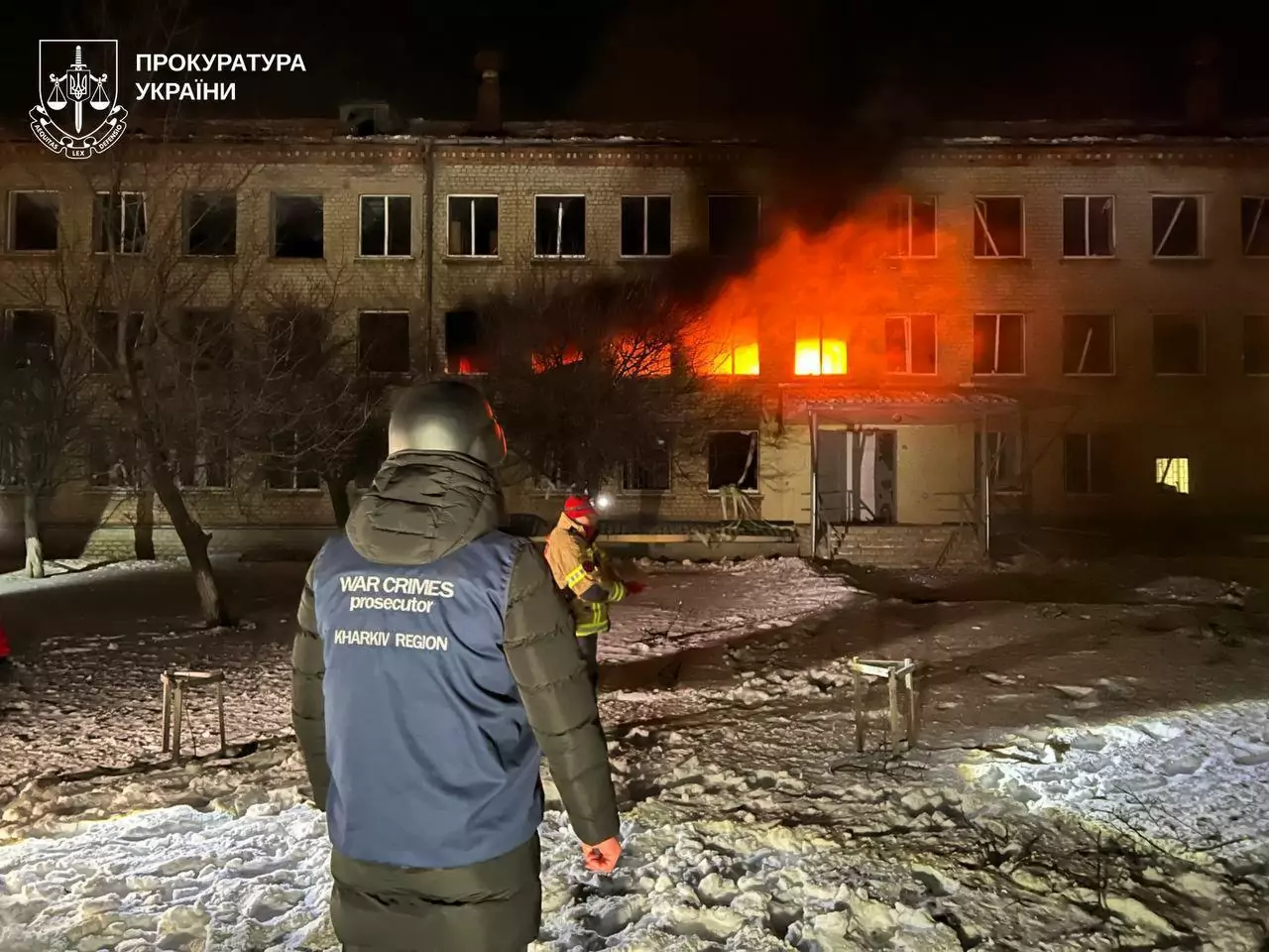 A man standing in front of the burning three-story building.