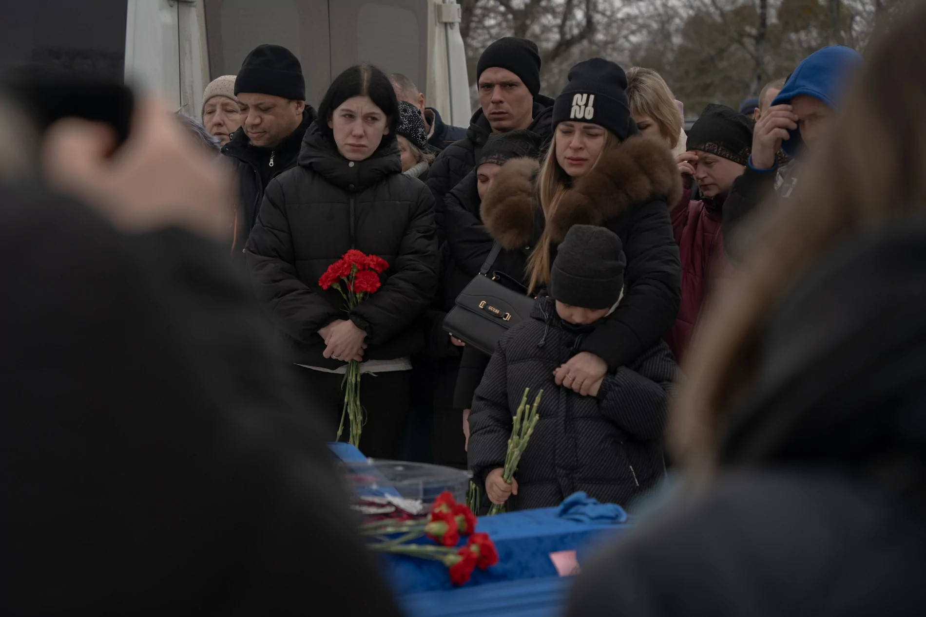 People standing in front of the coffin wrapped in blue fabric
