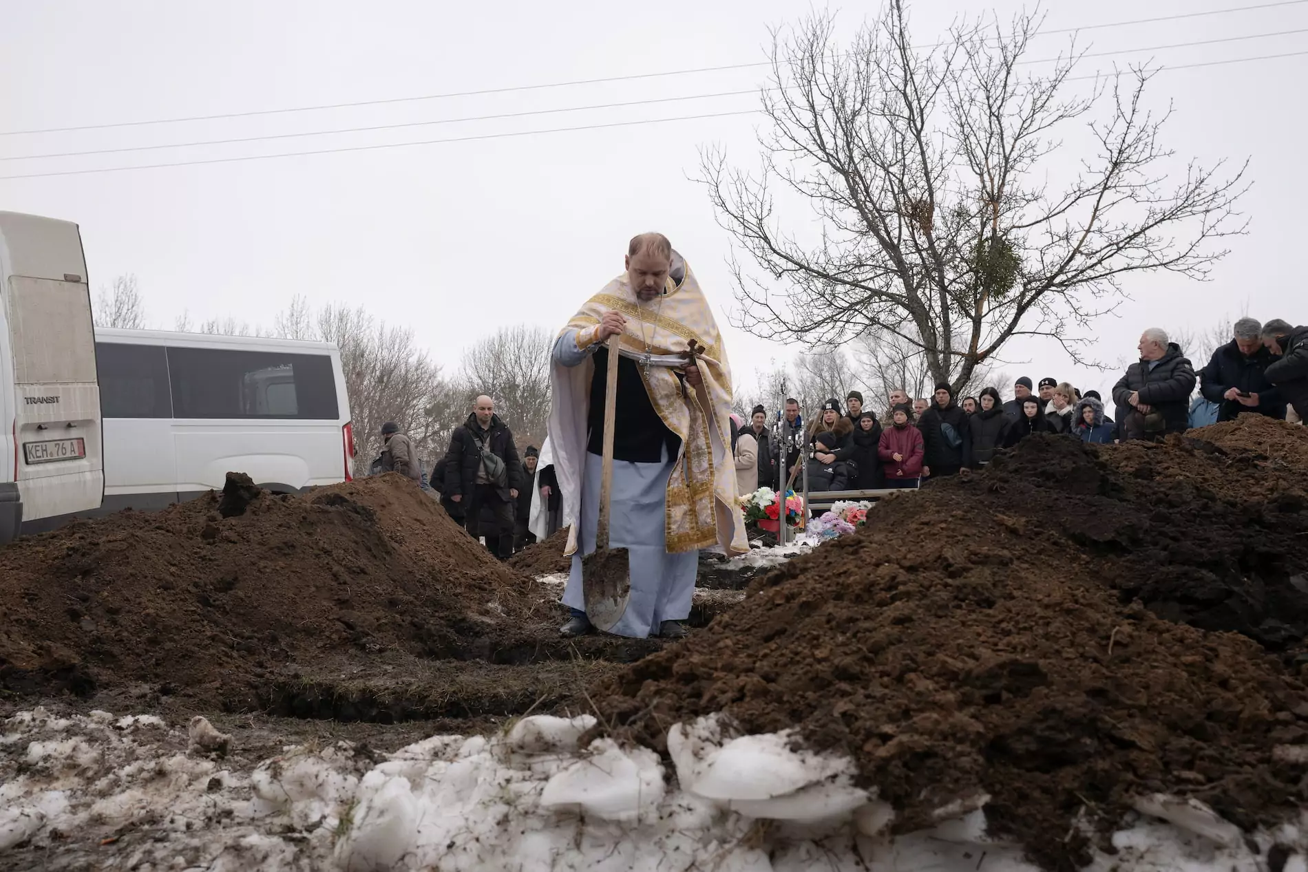 A priest walking above the graves with a shovel.