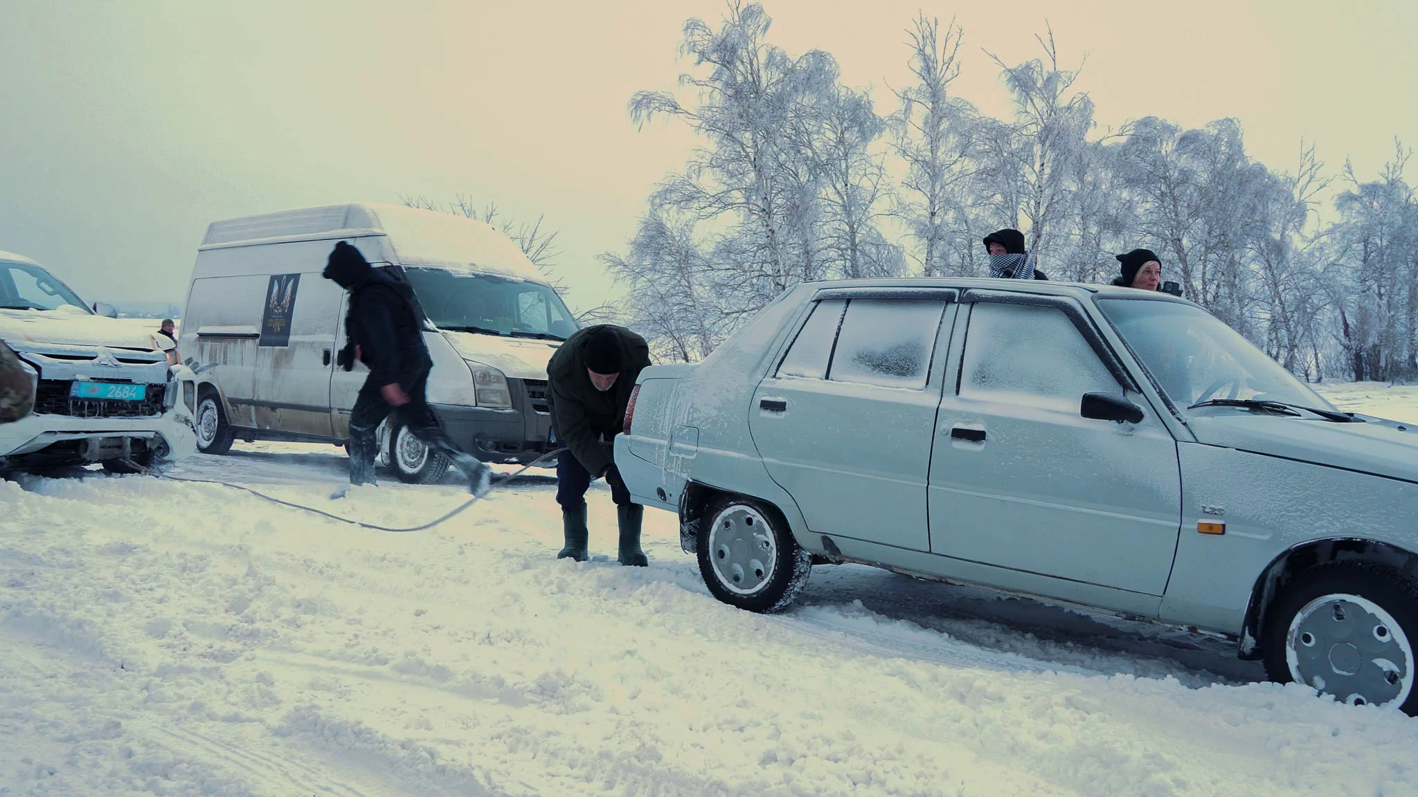 Police officers are helping to pull a civilian car out of the snow