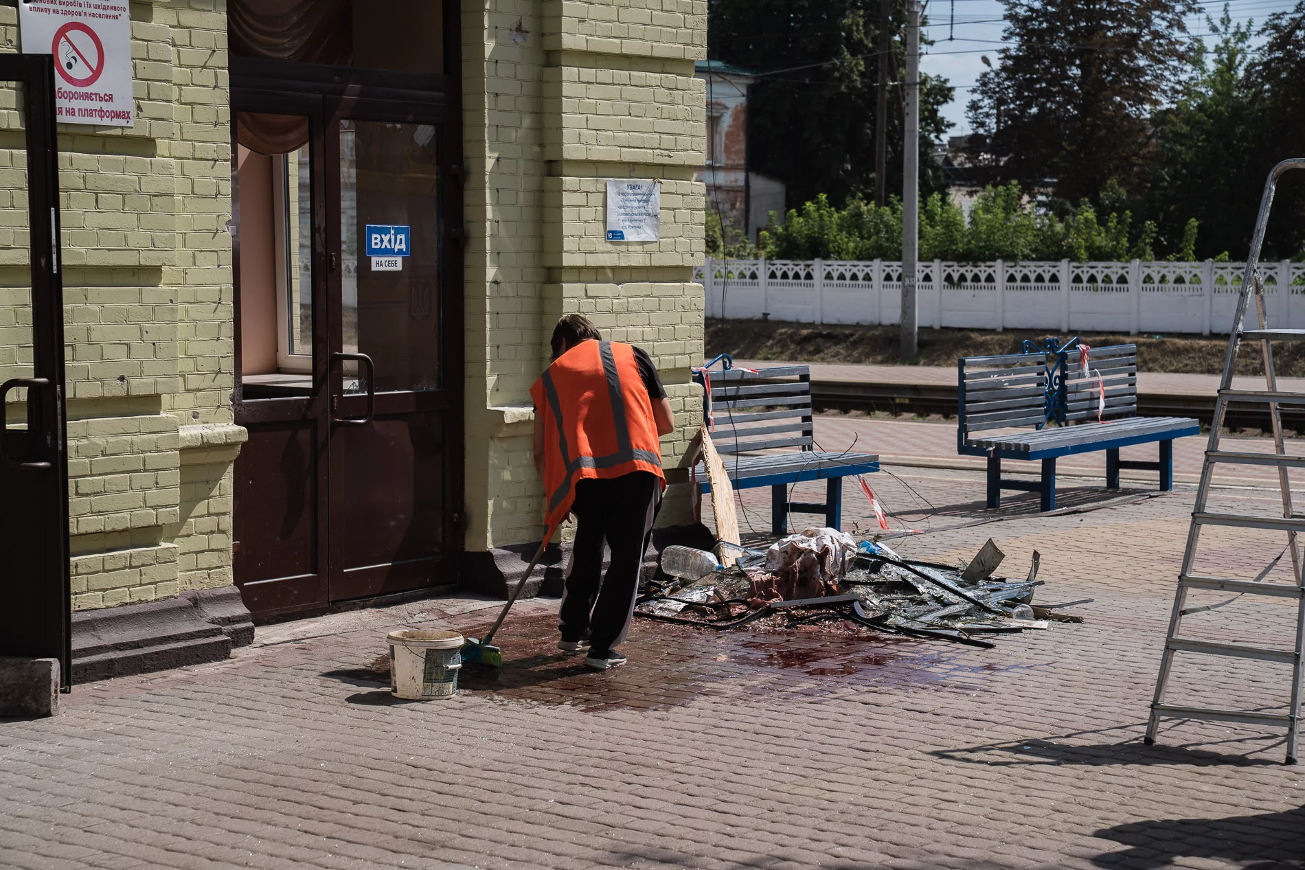 A man in the orange vest cleans up blood from the floor of the railway station in Lozova